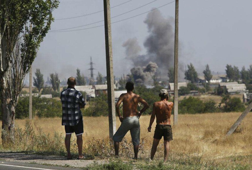 Местные жители смотрят как на дым во время обстрела Новоазовска, Восточная Украина, 27 августа 2014 года. Пророссийские силы обстреляли некоторые город на юго-востоке Украины в в среду во время контрнаступления на украинские части. 