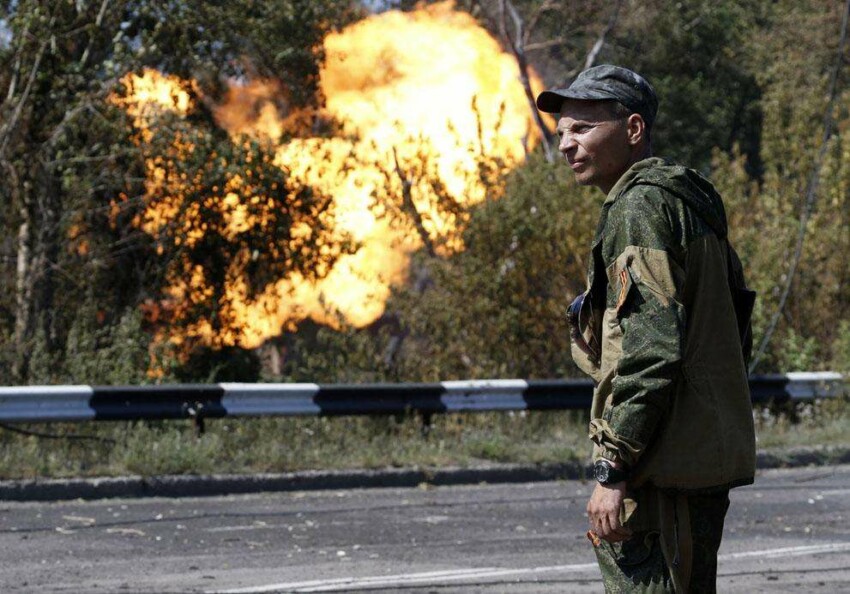 Пророссийский повстанец смотрит на огонь из газопровода после обстрела Донецка 15 августа 2014 года.