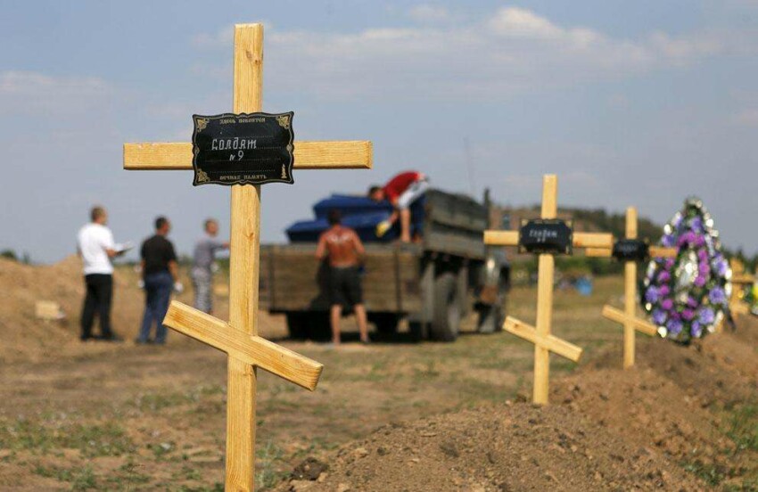 Разгрузка грузовика с гробами возле могил пророссийских повстанцев на кладбище на окраине Донецка. 21 августа 2014 года. Надпись на кресте: "Солдат номер 9".