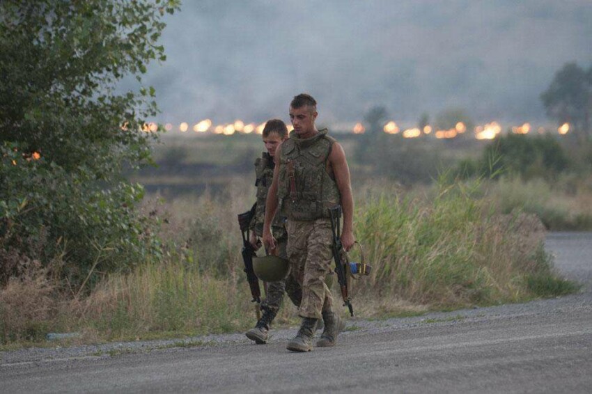 Украинские солдаты проходят мимо горящего поля после того как их обстреляли возле Иловайска 14 августа 2014 года. 