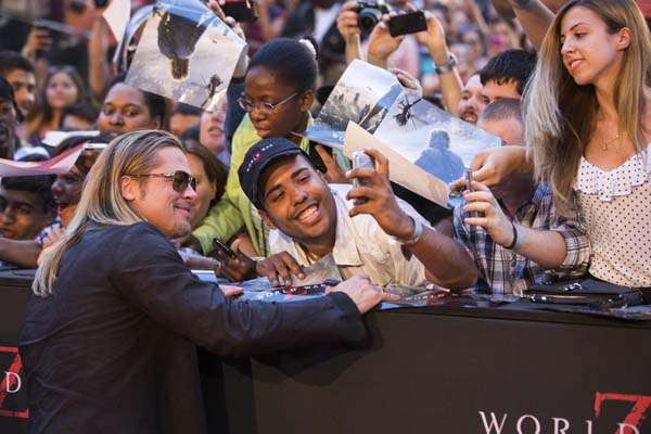 Cast member and producer Brad Pitt poses with a fan for a photo as he arrives for the premiere of the film "World War Z" in New York