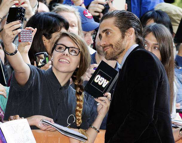 Jake Gyllenhaal poses for pictures with fans as he arrives for the "Enemy" screening at the 38th Toronto International Film Festival in Toronto