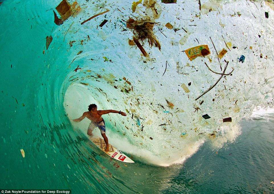 Серфер в покрытой мусором бухте на Яве, в Индонезии - наиболее густонаселенном острове в мире