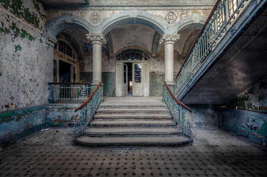 abandoned entry hall with staircase and pillars